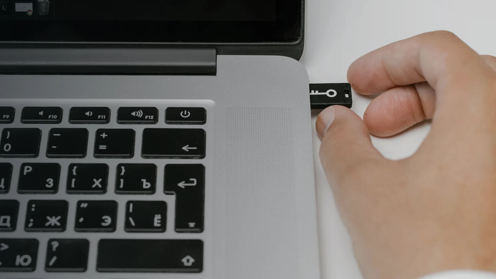 Рука подключает USB-накопитель к ноутбуку